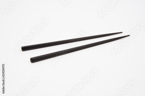 Black wooden chopsticks isolated on white background © Akmalism