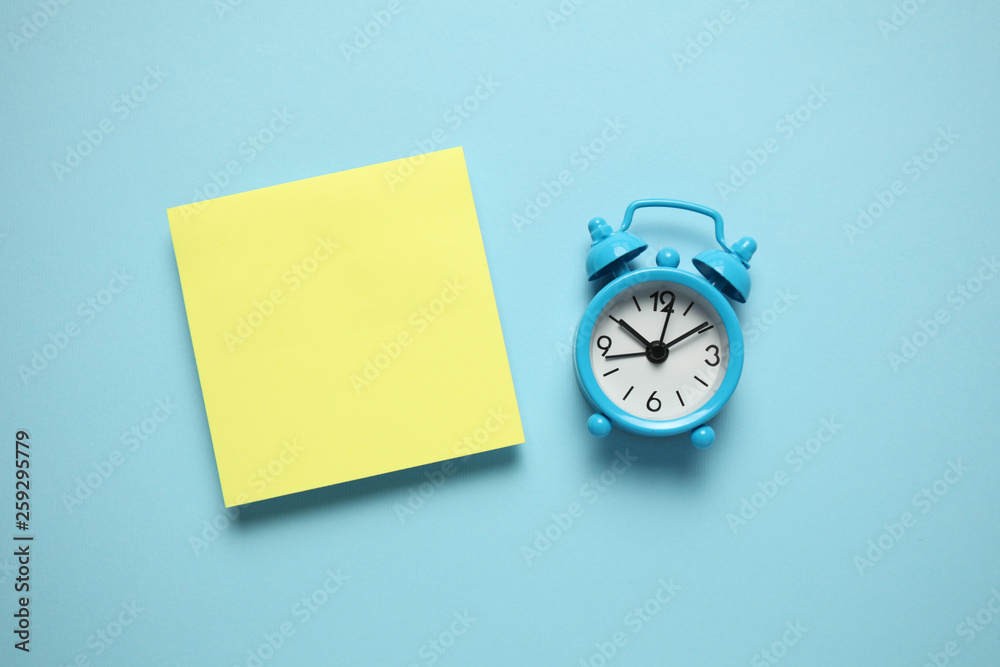Blue alarm clock and a reminder note. Time management concept. Copy space for text. Blue alarm clock and a reminder note. Time management concept. Copy space for text.