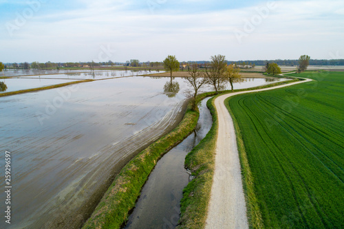Flooded fields for rice cultivation in the Po Valley, Italy. Panoramic aerial view. Typical countryside landscape of northern Italy with dirt roads, fields and ancient farms.