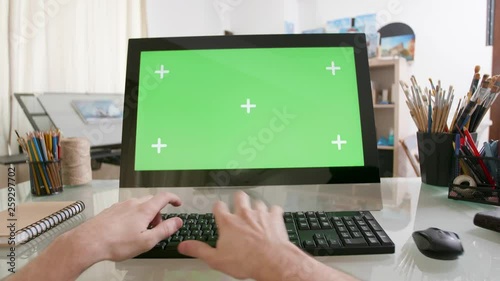 View on male hands working on a computer with green screen on a glass table. Artists point of view working on a computer. photo