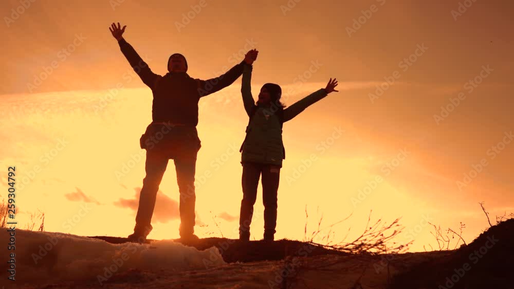father and daughter teamwork happy family tourists silhouette concept. team dad and daughter on top of a mountain at sunset raise hands to the top with backpacks. winning travel livestyle business