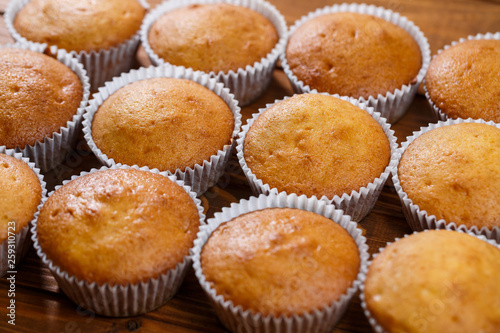 Homemade muffins in paper wrap on wooden board