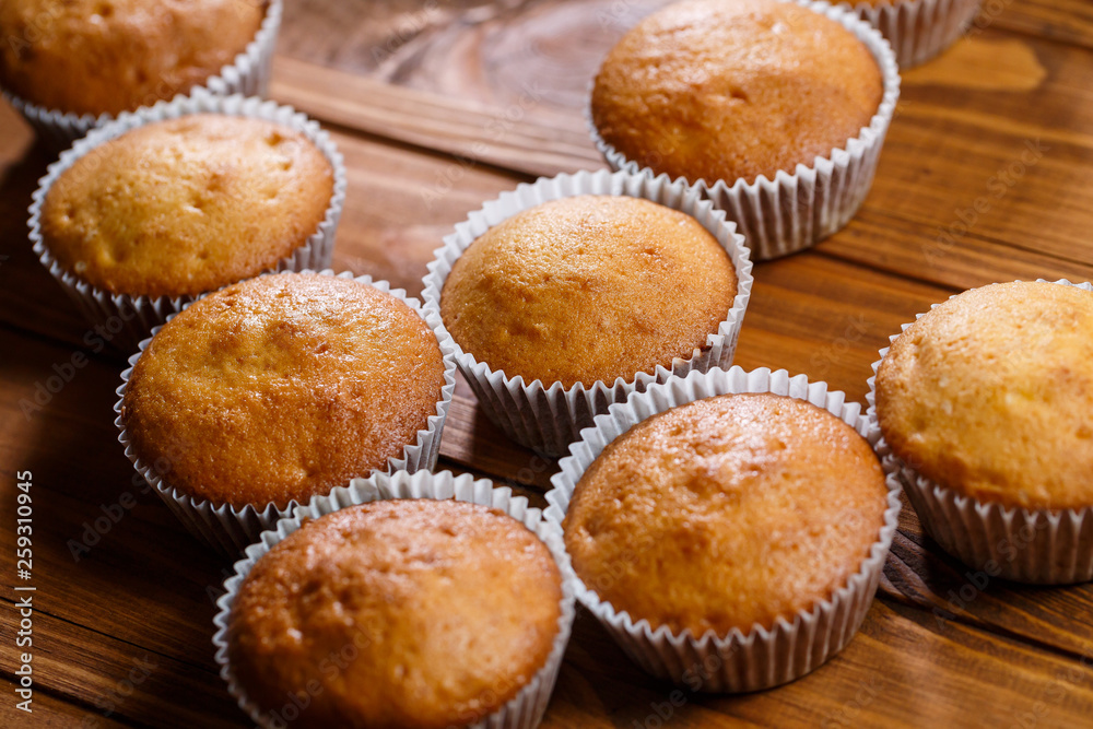 Homemade muffins in paper wrap on wooden board