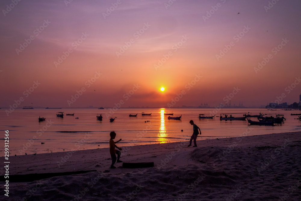 Silhouette of a boys enjoying the sunrsie at the beach in Penang Malaysia