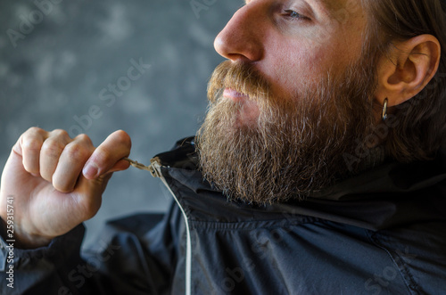 Man with a Beard Zip Up the Zipper in a Black Sports Jacket. Youth Type of Clothing Concept