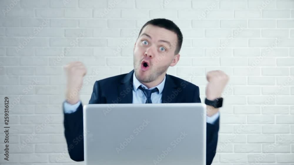 Businessman showing thumbs up while using laptop in office Businessman showing thumbs up while using laptop in office