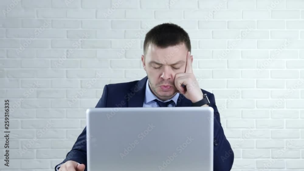 Thoughtful serious young man lost in thoughts in front of laptop Thoughtful serious young man lost in thoughts in front of laptop
