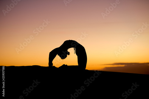 Fototapeta Naklejka Na Ścianę i Meble -  Fantastic moves from a yoga instructor make for fantastic silhouettes