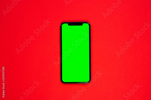 iPhone XS, smartphone, green screen on Red background top view
