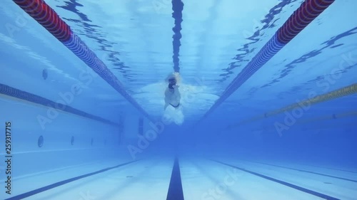 Muscular man under water in a swimming pool in slow motion