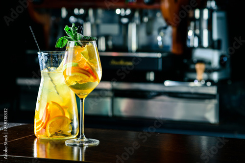 Closeup glass of white sparkling wine sangria decorated with citrus slices at bright bar counter background. photo