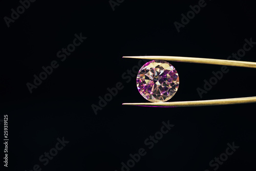 colorful pure sparkling diamond in tweezers isolated on black