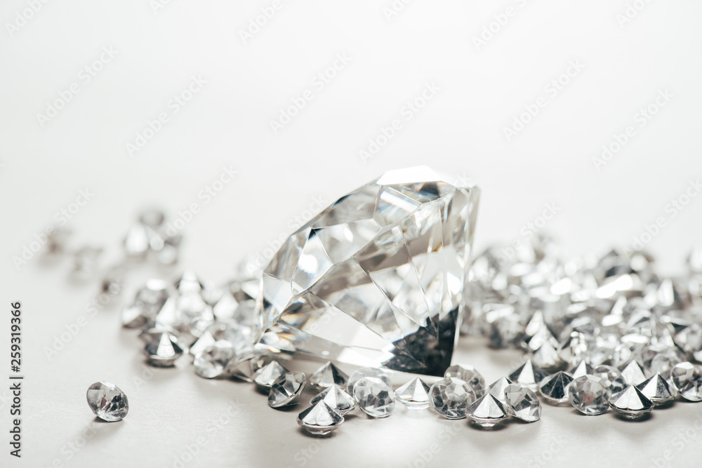 selective focus of sparkling pure big diamond among small on white background selective focus of sparkling pure big diamond among small on white background
