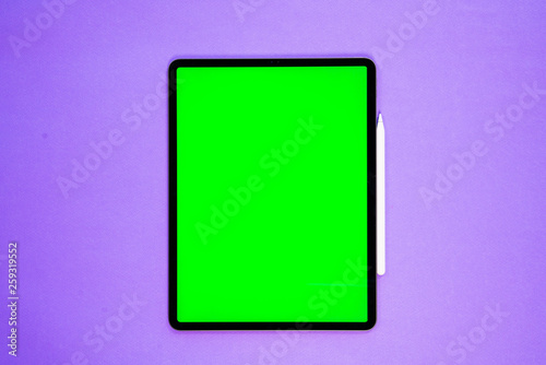 new tablet on a Violet background with a keyboard and pen, and green screen  top view