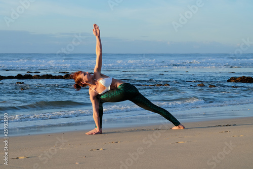A awesome yoga instructor does some stretches and poses on the beach 