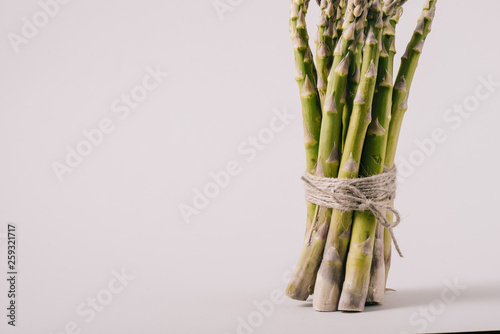 bunch of green fresh asparagus tied with rope on grey background