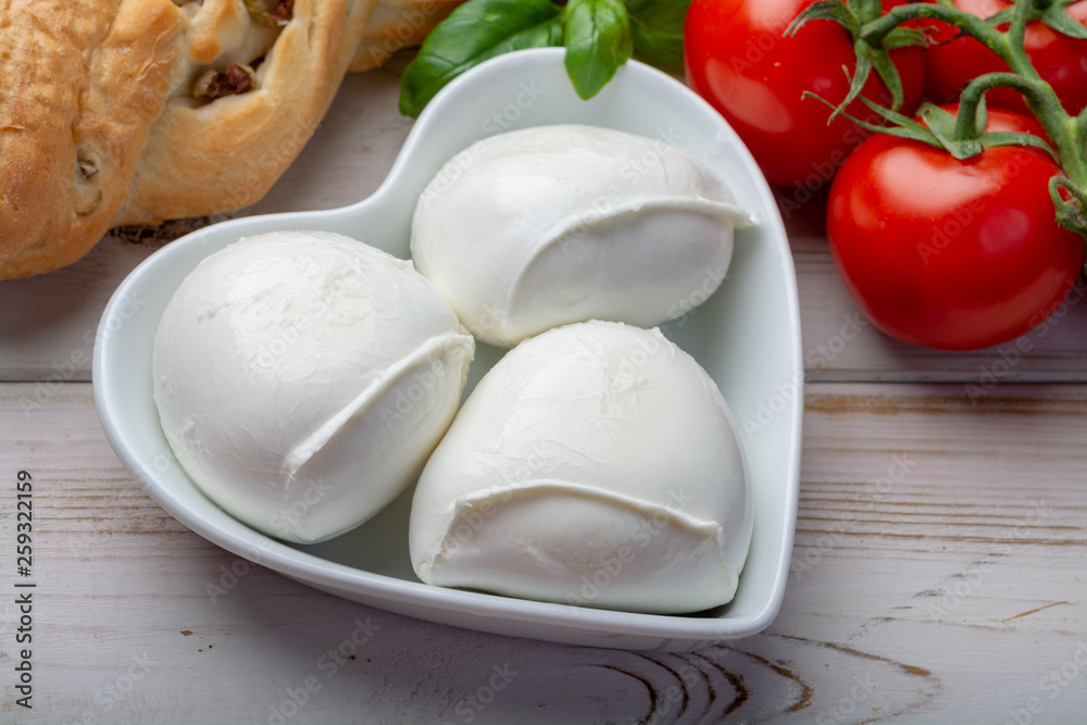 Love mozzerella, balls of buffalo mozzarella, soft Italian scheese made from the milk of Italian Mediterranean buffalo in heart shaped plate Love mozzerella, balls of buffalo mozzarella, soft Italian scheese made from the milk of Italian Mediterranean buffalo in heart shaped plate