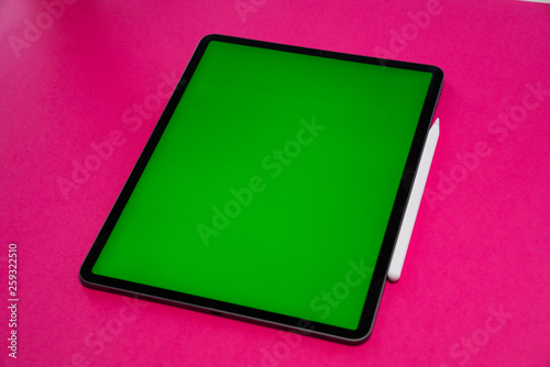 new iPad, tablet on a Pink background with a keyboard and pen, and green screen top view