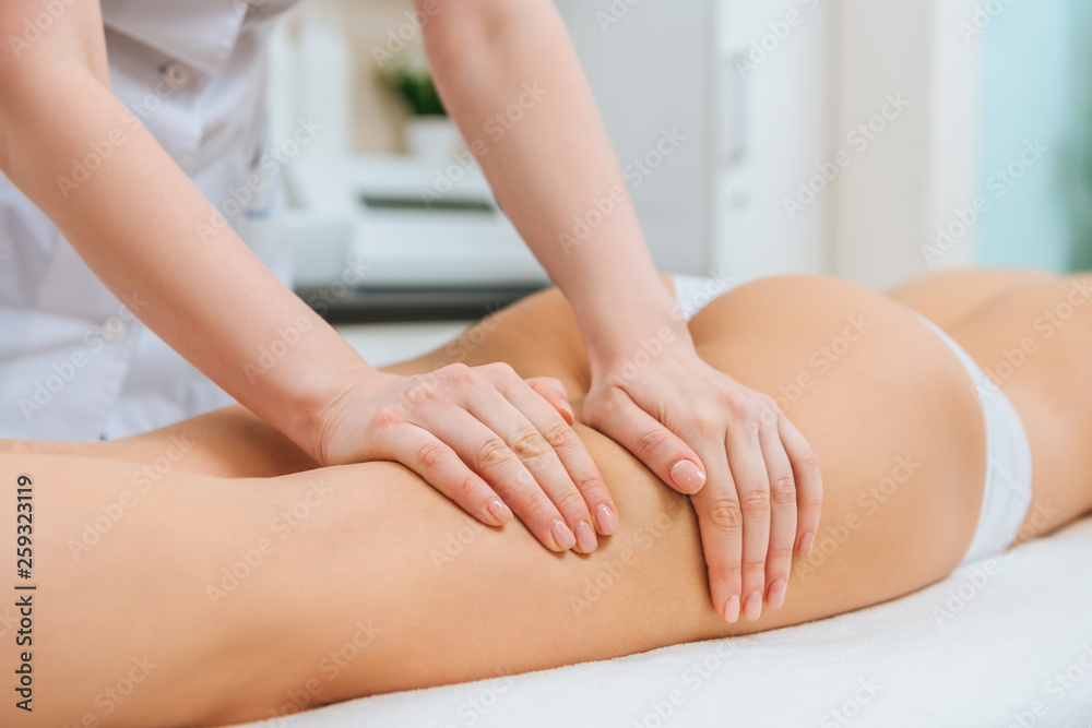 Partial view of masseur doing leg massage to woman Partial view of masseur doing leg massage to woman