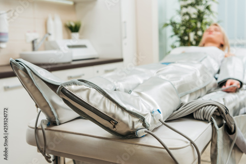 Selective focus on woman lying on beauty couch during pressotherapy session