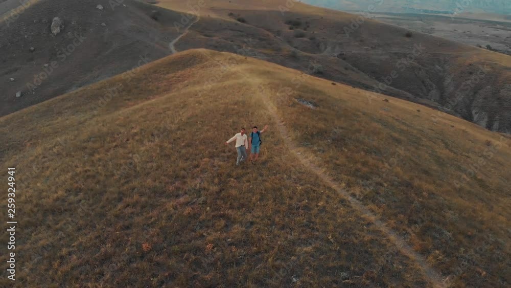 A man with a backpack walks the hills against the backdrop of a valley with mountains From a drone A man with a backpack walks the hills against the backdrop of a valley with mountains From a drone