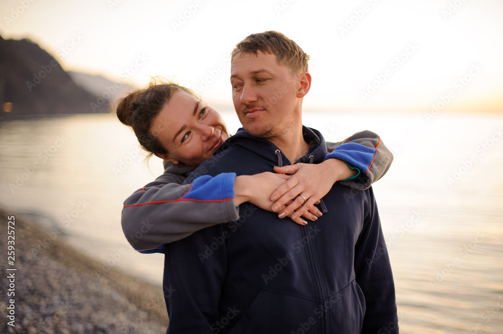 Young smiling girl hugging her boyfriend from behind