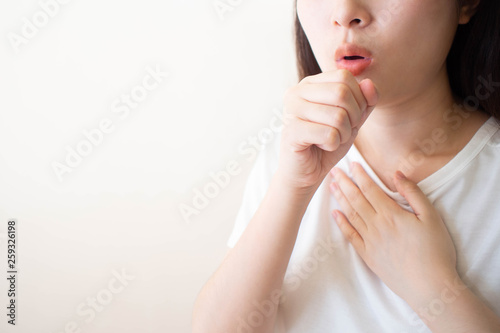 Young ill female have a cough and sore throat over white background. Causes of cough include pneumonia, bronchitis, allergy, asthma, COPD, TB or respiratory tract infection. Copy space. Health care. photo