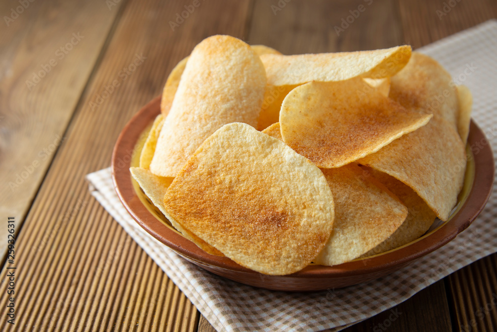 Potato chips in bowl and fresh potato. Delicious crispy snack. Rustic style. Potato chips in bowl and fresh potato. Delicious crispy snack. Rustic style.