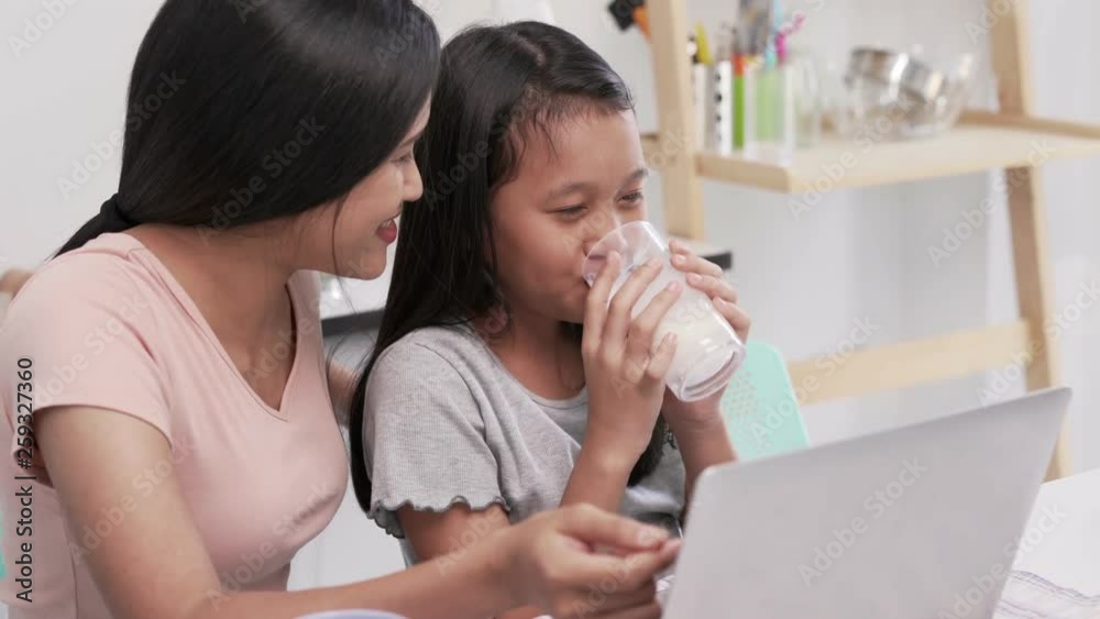 School girl drinking milk while and Mother together in morning, family breakfast. Mom and daughter Spend Time Holiday Eating Breakfast, parent or teachers and child on Child care center, host family School girl drinking milk while and Mother together in morning, family breakfast. Mom and daughter Spend Time Holiday Eating Breakfast, parent or teachers and child on Child care center, host family