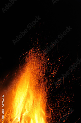 Flame of a burning fire with sparks in the night on a black background. Close-up