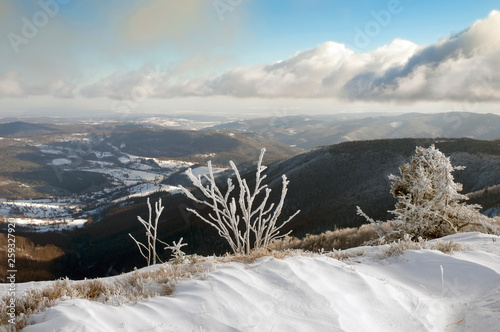 A frosty day at the top of a mountain on a sunny day with blue sky, clouds and a beautiful panorama