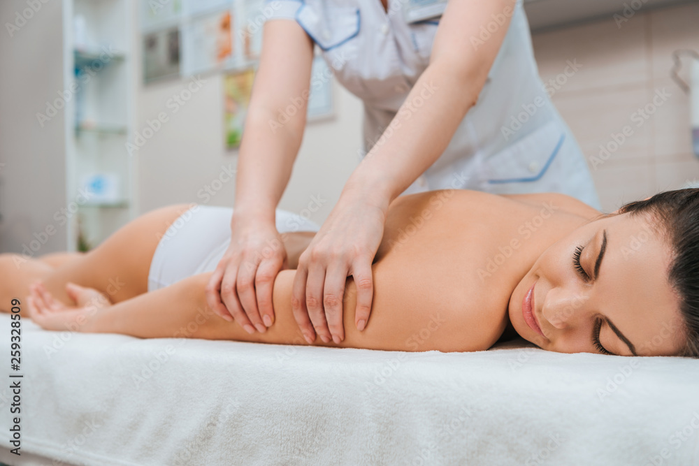 Fototapeta premium Cropped view of masseur doing arm massage to girl on massage table