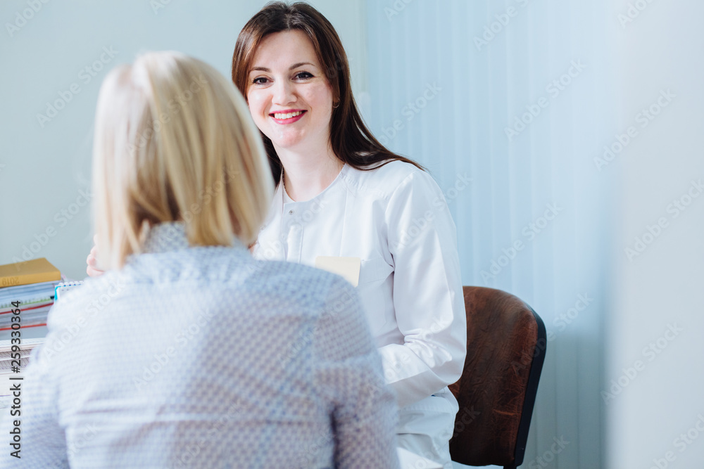 Obraz premium Back view of blond woman patient is consulting with doctor gynecologist in medical office. Close up