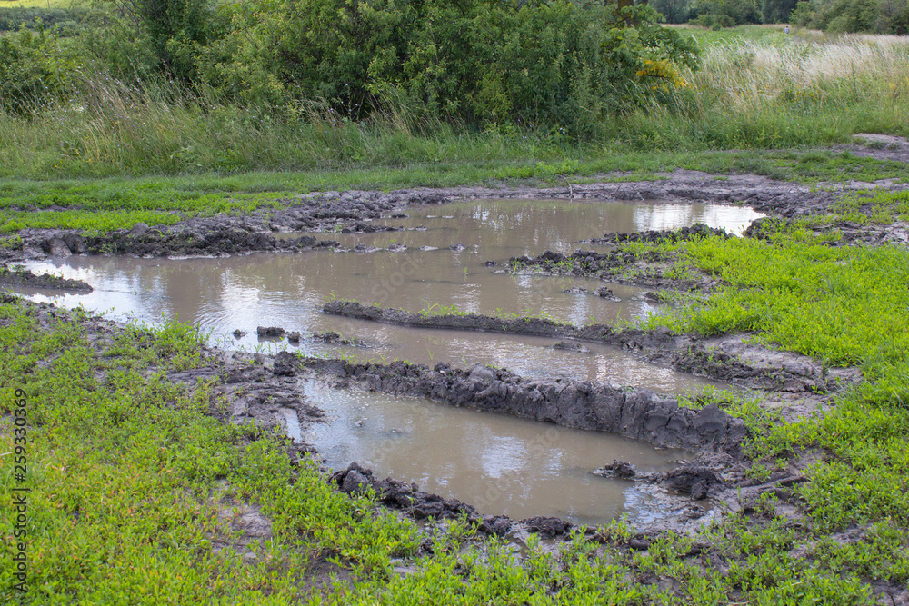 dirt road with puddle,rural roads in the summer after the rains with a large puddle dirt road with puddle,rural roads in the summer after the rains with a large puddle
