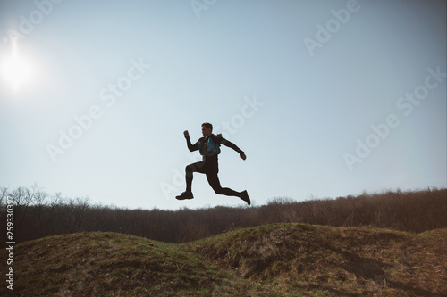 Man running in a park or forest against trees background.