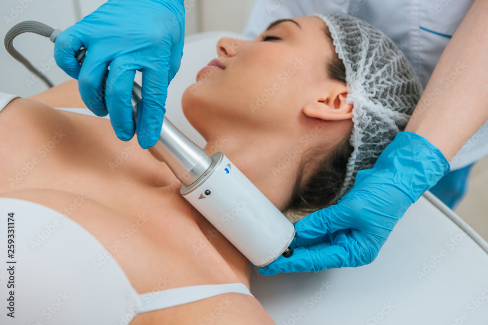 Cropped view of cosmetologist doing therapy for neck Cropped view of cosmetologist doing therapy for neck