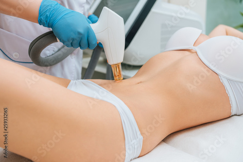 Cropped view of cosmetologist in rubber gloves doing laser treatment