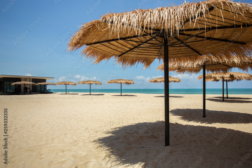 Fototapeta premium Straw umbrella on the beach for summer vacation tropics,Concept: Lifestyle for leisure travel,symbol tourism for island By the sea