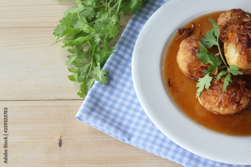 Sweet and sour eggs in white dish with coriander on wooden table. Sweet and sour eggs in white dish with coriander on wooden table.