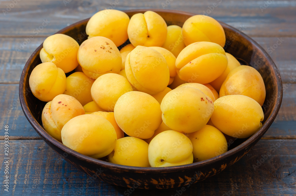 Ripe apricots in a clay bowl.