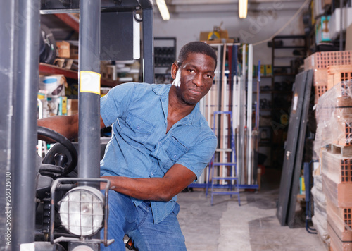 African American worker of building materials warehouse working on forklift truck