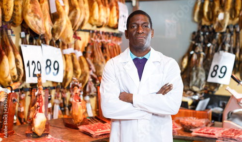 Butcher posing near ham counter