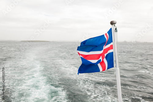  Icelandic flag on the background of the ocean. A flag on a ship develops in the wind during a whale watching tour