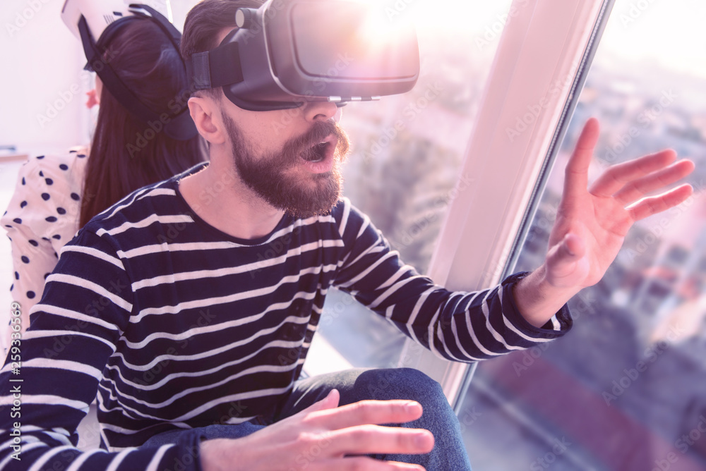 Shocked young male person enjoying virtual reality interaction Shocked young male person enjoying virtual reality interaction