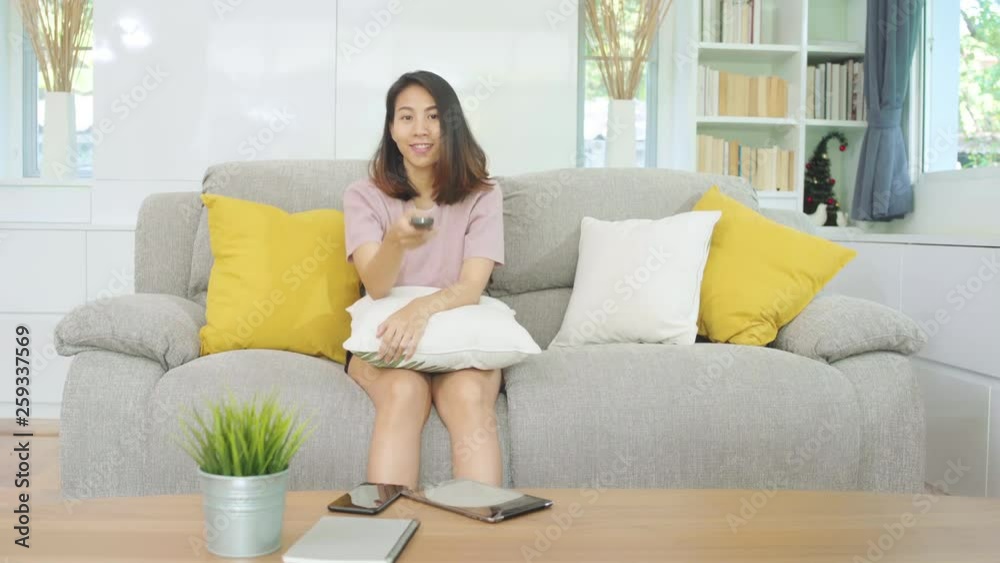 Young Asian teenager woman watching TV at home, female feeling happy lying on sofa in living room. Lifestyle woman relax in morning at home concept. Young Asian teenager woman watching TV at home, female feeling happy lying on sofa in living room. Lifestyle woman relax in morning at home concept.