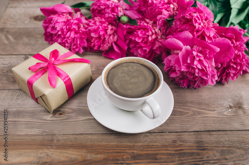 Pink peony flowers gift box cup of coffee and notes good morning on rustic table. Mothers day or Womens day