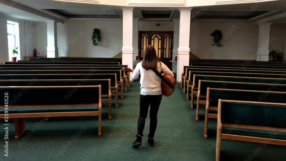 Curly haired woman playing acoustic guitar in empty hall, singing and dancing Curly haired woman playing acoustic guitar in empty hall, singing and dancing