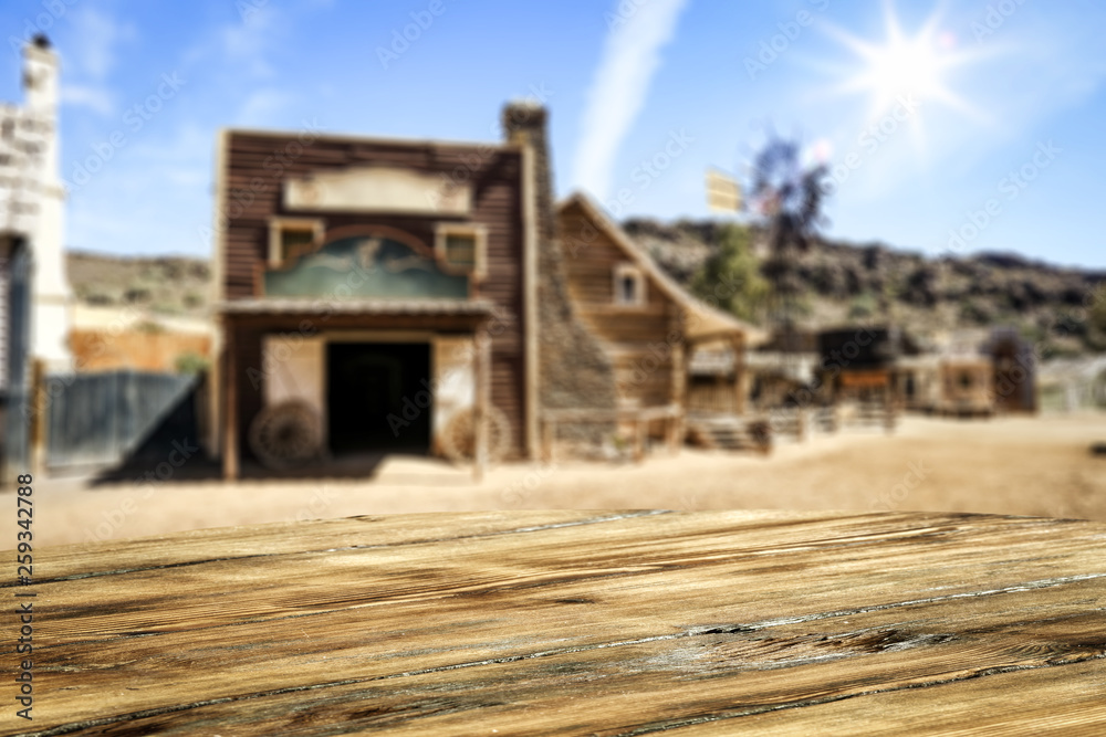 Wooden old table of free space for your product. Blurred background of Wild West city in America. Wooden old table of free space for your product. Blurred background of Wild West city in America.