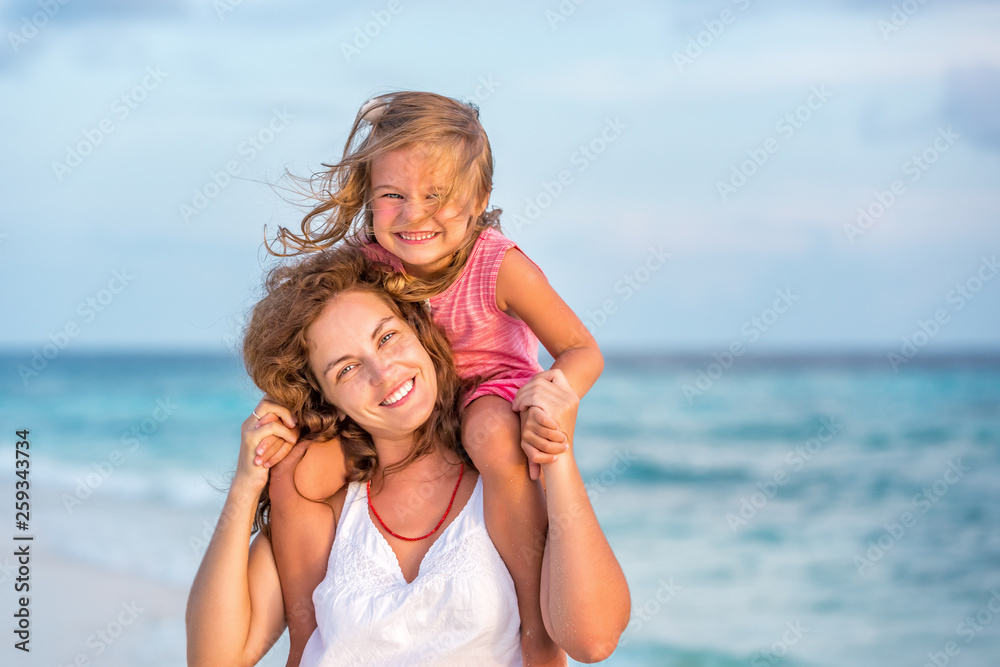 Portrait of happy mother and little daughter on sunny beach on Maldives at summer vacation Portrait of happy mother and little daughter on sunny beach on Maldives at summer vacation