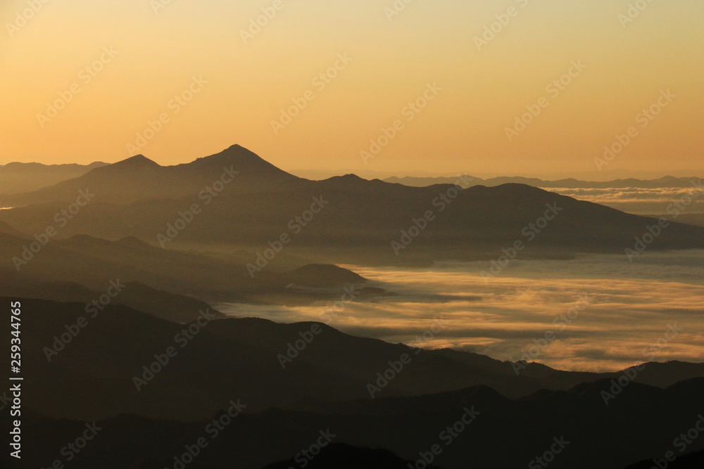 東北飯豊山　山頂直下本山小屋から　朝焼けに煙る会津磐梯山と雲海の下に眠る会津の街と猪苗代湖